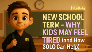 Smiling child in a SOLO Martial Arts uniform, confidently in school class room